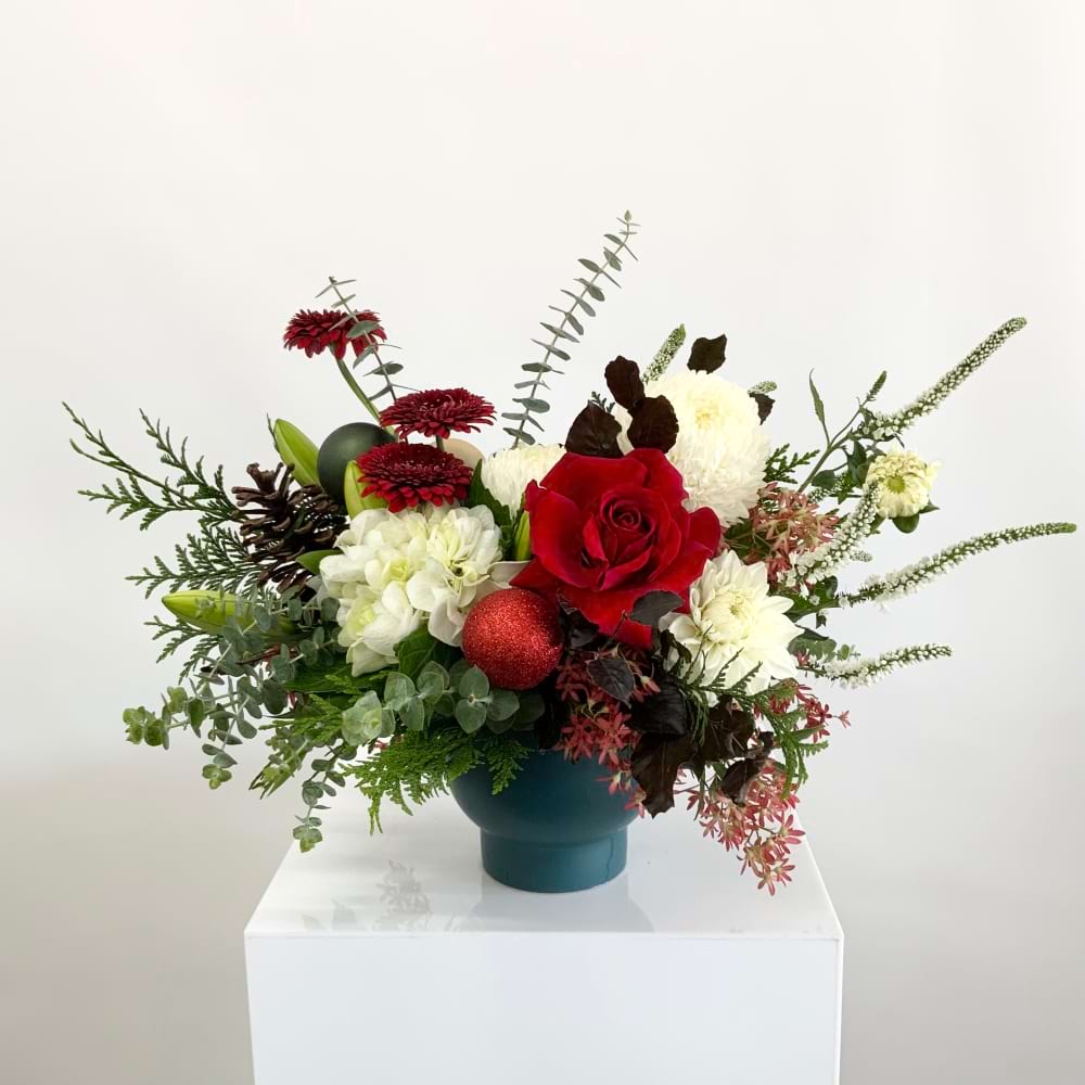 A festive bouquet of red and white Christmas flowers with green foliage in a vase as a Christmas table centrepiece