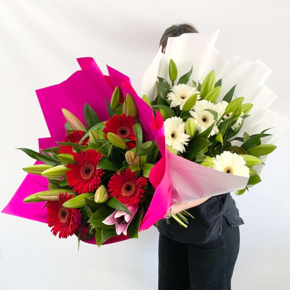 A young woman holding 2 large bouquets of white Oriental Lilies and Gerbera flowers