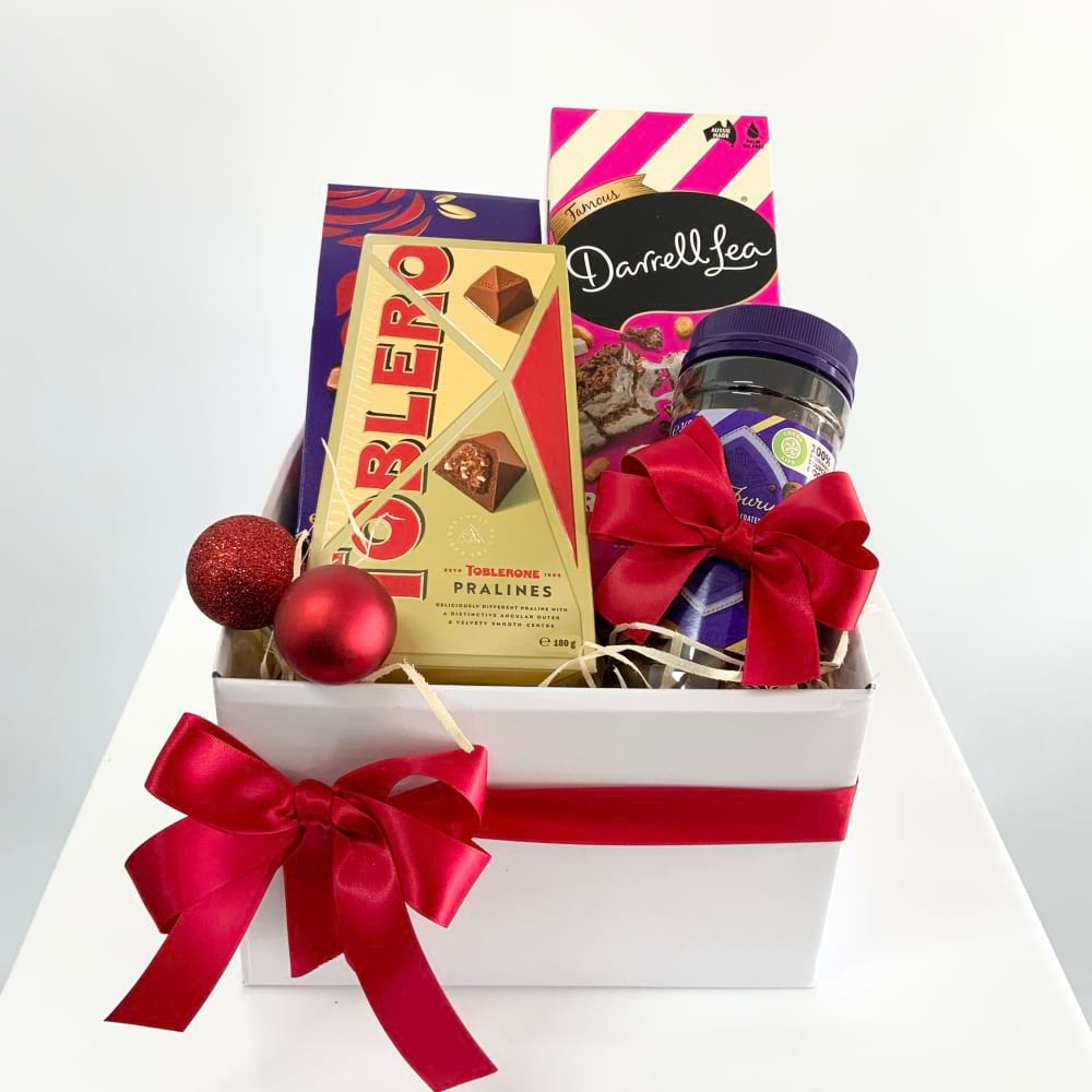 A white gift box tied with a red bow and filled with a selection of favourite Christmas chocolates
